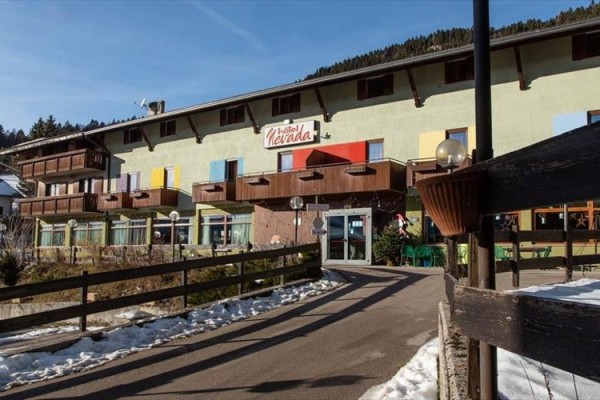 Hotel s drevenými balkónmi a nápisom na fasáde v horskej oblasti.
