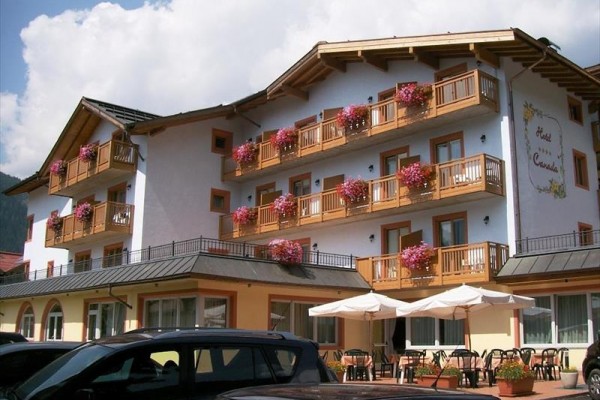Trojposchodový hotel s drevenými balkónmi zdobenými kvetinami.