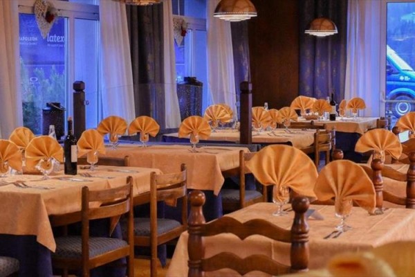 Elegantne prestretá reštaurácia s drevenými stolmi a stoličkami a poskladanými oranžovými servítkami.  