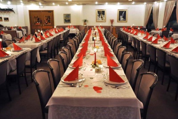 Dlhý banketový stôl s červenými obrúskami a sviečkami v elegantnej jedálni.