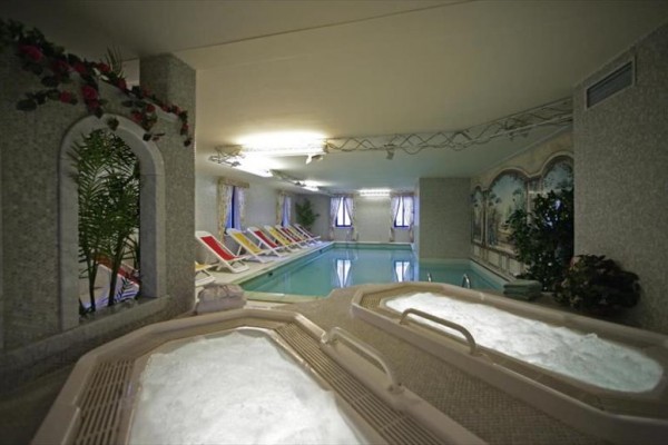 Vnútorný bazén s vírivkou a lehátkami na relax.