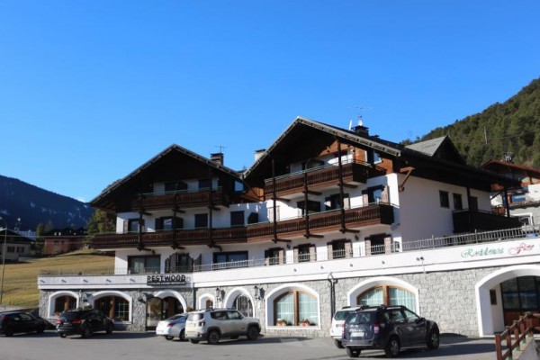 Hotel v alpskom štýle s parkoviskom pred ním.