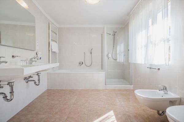 Svetlá kúpeľňa s vaňou, sprchovacím kútom, dvojitým umývadlom a bidetom.
