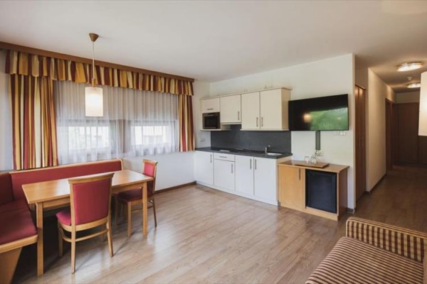 Kuchynský kút v apartmáne s jedálenským stolom a štyrmi stoličkami.