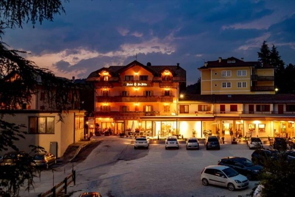 Hotel osvetlený počas súmraku s niekoľkými autami zaparkovanými pred ním.  