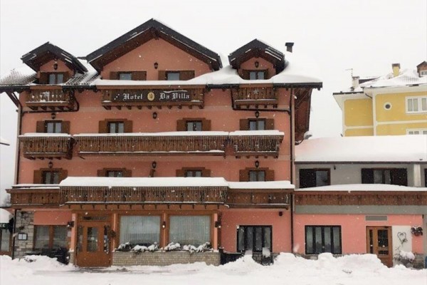 Ružový hotel s drevenými balkónmi pokrytými snehom.