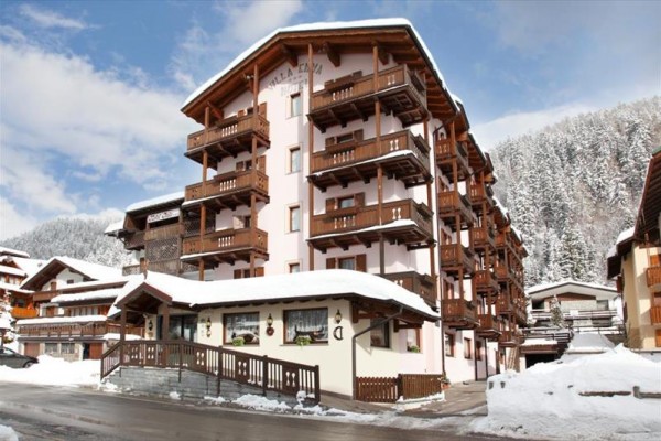 Horská apartmánová budova so zasneženou krajinou.