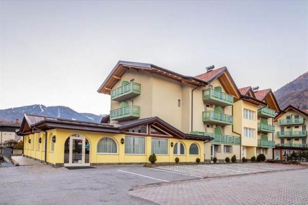 Žltá budova hotela s balkónmi v horskej oblasti.