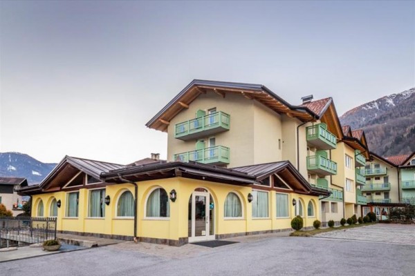 Žltá budova s balkónom v horskom prostredí.  