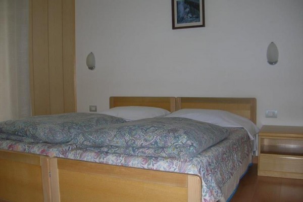 Drevená manželská posteľ s nočným stolíkom v spálni.