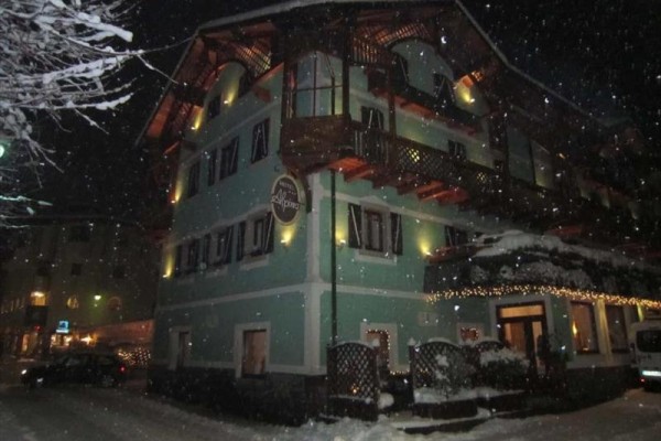 Zasnežený hotel v tme s osvetlenou fasádou.