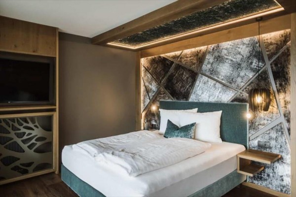 Moderná spálňa s elegantnou manželskou posteľou a dizajnovou tapetou na stene.