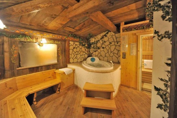 Útulná drevená sauna s vírivkou a posedením v rustikálnom štýle.  