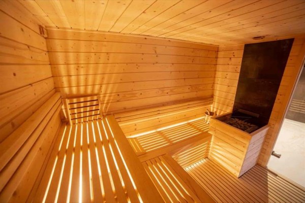 Drevená sauna s lavičkami a kachľami.