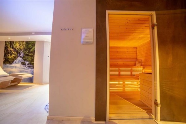 Sauna a relaxačná miestnosť s ležadlami a obrazom prírody.