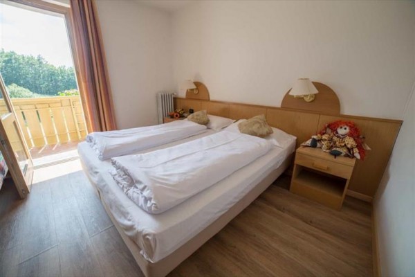 Spálňa s dvojlôžkom a otvorenými dverami na balkón.