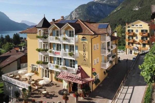 Hotel pri jazere s horami v pozadí.