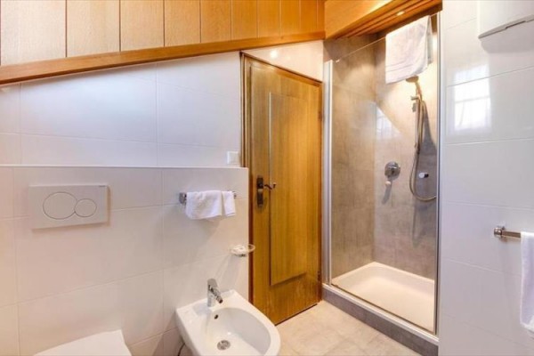 Kúpeľňa s bielymi obkladmi, sprchovacím kútom a bidetom.