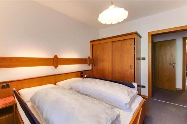 Spálňa s manželskou posteľou, drevenou skriňou a dverami.