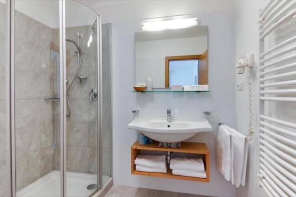 Moderná kúpeľňa so sprchovým kútom, umývadlom a zrkadlom.