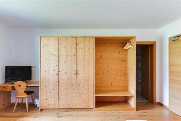 Drevený nábytok v izbe so šatníkovou skriňou, písacím stolom a televízorom.