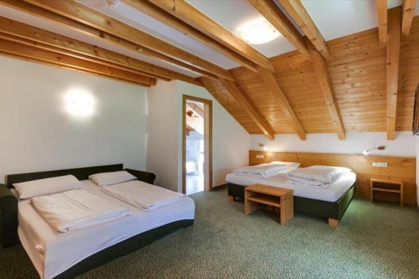 Dvojposteľová izba s drevenými stropmi a dvoma manželskými posteľami.