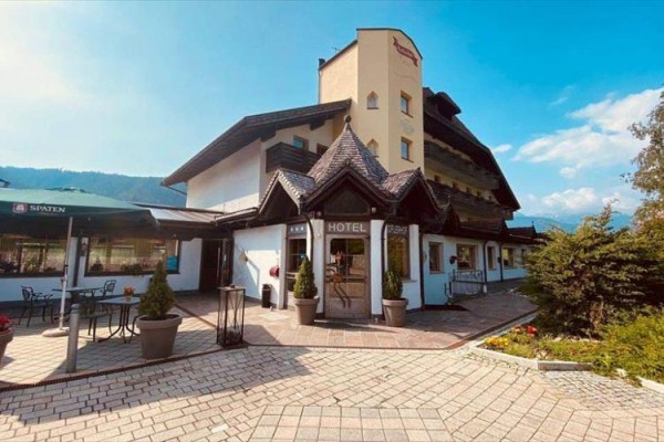 Hotel s drevenými prvkami a terasou v slnečnom prostredí.