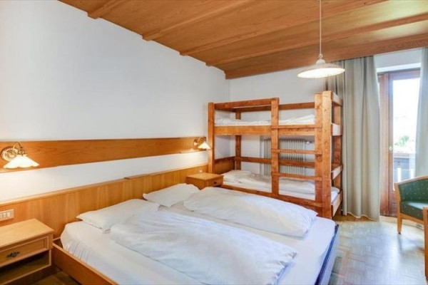 Izba s manželskou posteľou, poschodovou posteľou a balkónovými dverami.