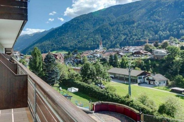 Výhľad z balkóna na horskú krajinu s dedinou v údolí.