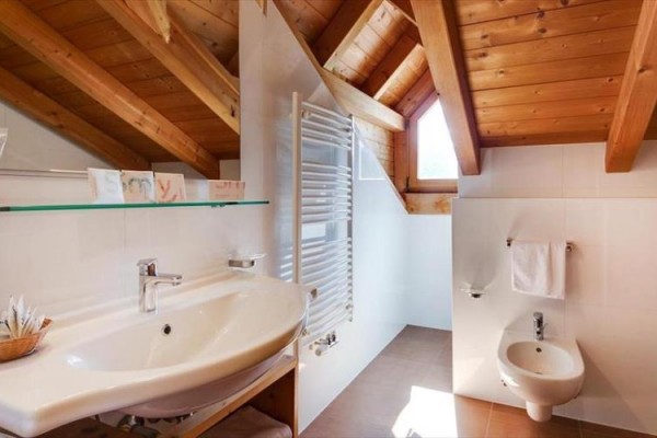 Kúpeľňa s dreveným stropom, umývadlom, bidetom a radiátorom.