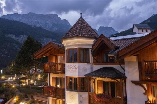 Hotel vo večernom osvetlení s horami v pozadí.