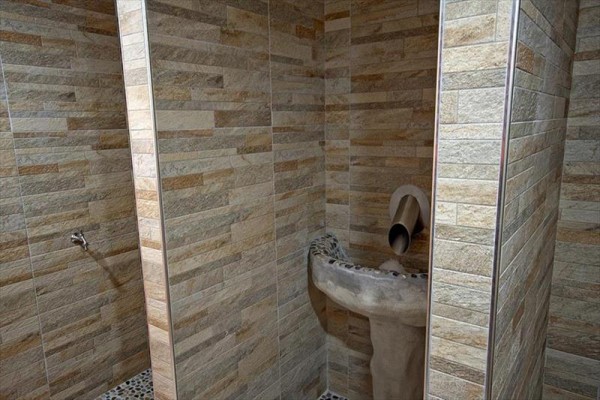 Kamenné umývadlo v kúpeľni s obkladom z keramických dlaždíc.