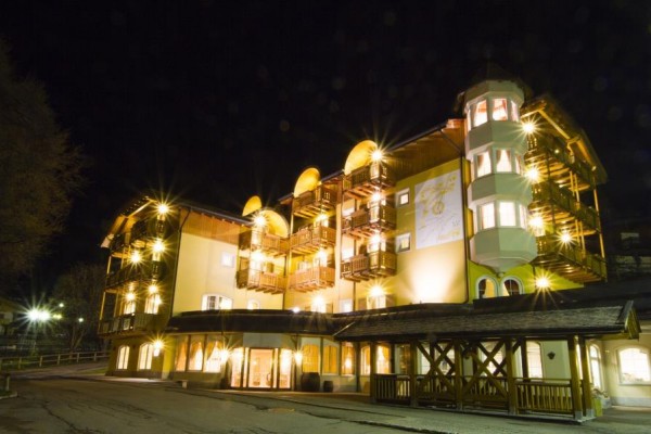Nočne osvetlený viacposchodový hotel s drevenými balkónmi.