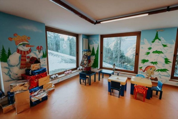 Detská herňa s vianočnou výzdobou, maľby snehuliaka a stromčekov na stenách.