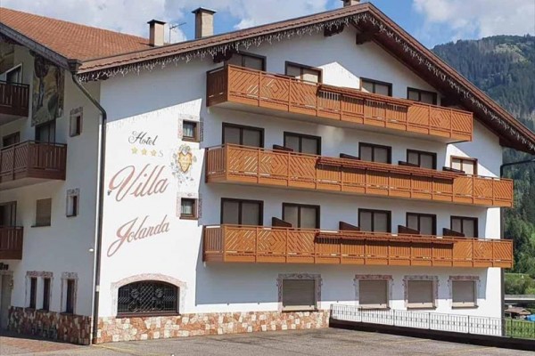 Biela budova hotela Villa Jolanda s drevenými balkónmi a nápisom na fasáde.