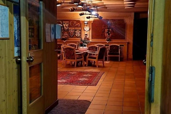 Pohľad do dreveného interiéru s jedálenským stolom a stoličkami, osvetlený teplým svetlom.