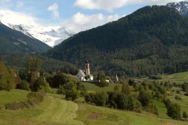Malebná dedina s kostolom obklopená horami a lesmi.