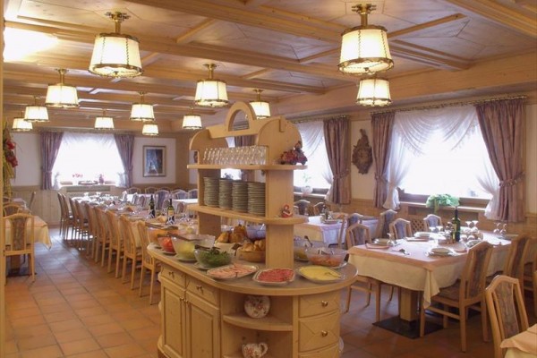 Reštaurácia s prestretými stolmi a bufetom s jedlom uprostred.