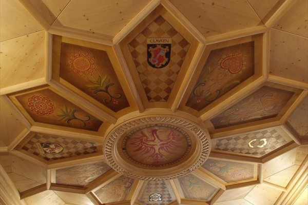 Drevený strop s geometrickým vzorom a zdobenými panelmi.