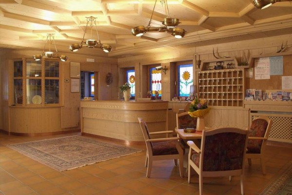 Recepcia s dreveným nábytkom a dekoráciami, farebnými oknami a koberčekmi.
