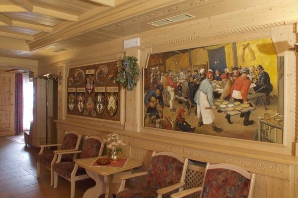 Interiér miestnosti so zdobeným dreveným obkladom a nástennou maľbou.