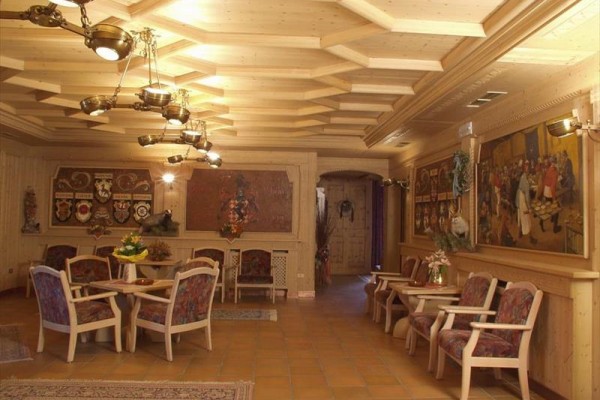 Elegantný drevený interiér s niekoľkými stolmi a obrazmi na stenách.