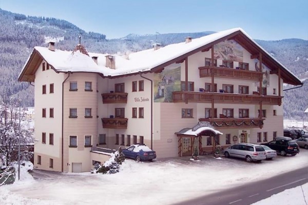 Horský hotel so zasneženou strechou a výhľadom na zasnežené hory.