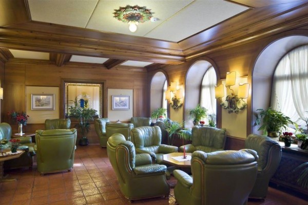 Elegantný salónik s koženými zelenými kreslami, kobercami a dreveným stropom.