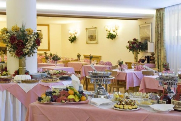 Luxusný bufet s rozmanitým jedlom v elegantnej reštaurácii s ružovými obrusmi a kvetinovými dekoráciami.