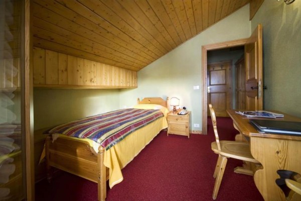 Jednolôžková izba so šikmým stropom a svetlým dreveným nábytkom.