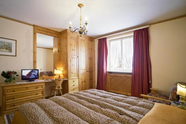 Útulná spálňa s dreveným nábytkom a lusterom na strope.