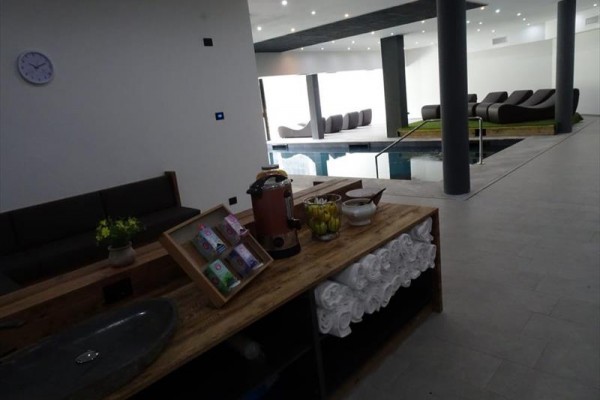 Moderný wellness priestor s bazénom a oddychovými ležadlami.