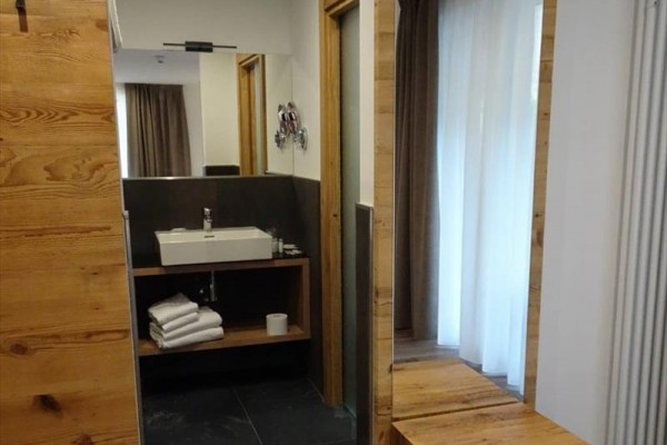Kúpeľňa s umývadlom na drevenej doske, skrinkou a zrkadlom.