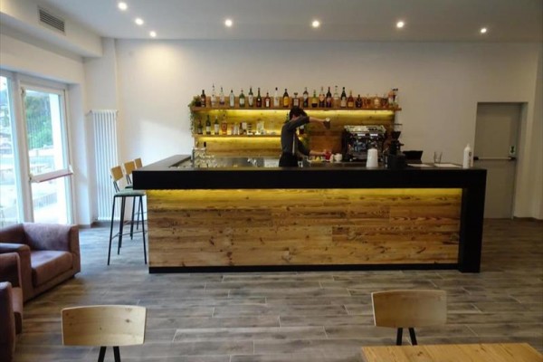 Moderný bar s barmanom pripravujúcim nápoj pred policou plnou fliaš alkoholu.